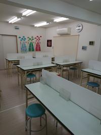 真っ白で明るい教室。コロナ感染対策として、机はパーテーションで仕切りあり。
