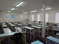 広い教室で間隔を空けて着席します。<br />
スタッフの前にはパネルを設置しています。