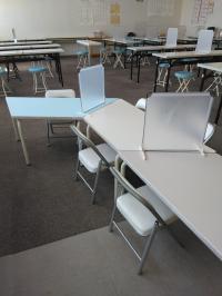 先生の前で学習できる幼児用の席があります。飛沫防止パネルを置いて指導しています。