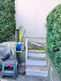 駐車場横のこちらの階段から建物の裏へお回りください。入口は裏にございます。