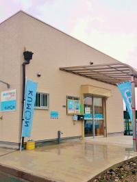 道に面した白い建物です。送迎の停車スペースもあります。