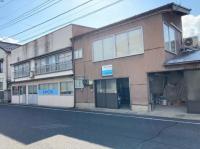 入り口は看板の下です。駐車場は左の家屋の左隣、ベビーカーは教室入口の中に置けます