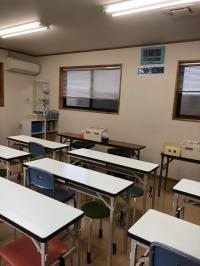 白を基調とした明るい教室で、密にならないように机の間隔を広くとっています。